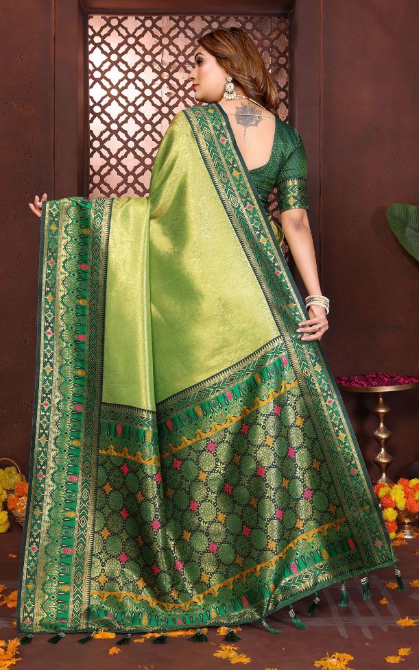 Woman wearing a green saree with intricate patterns in a decorated setting