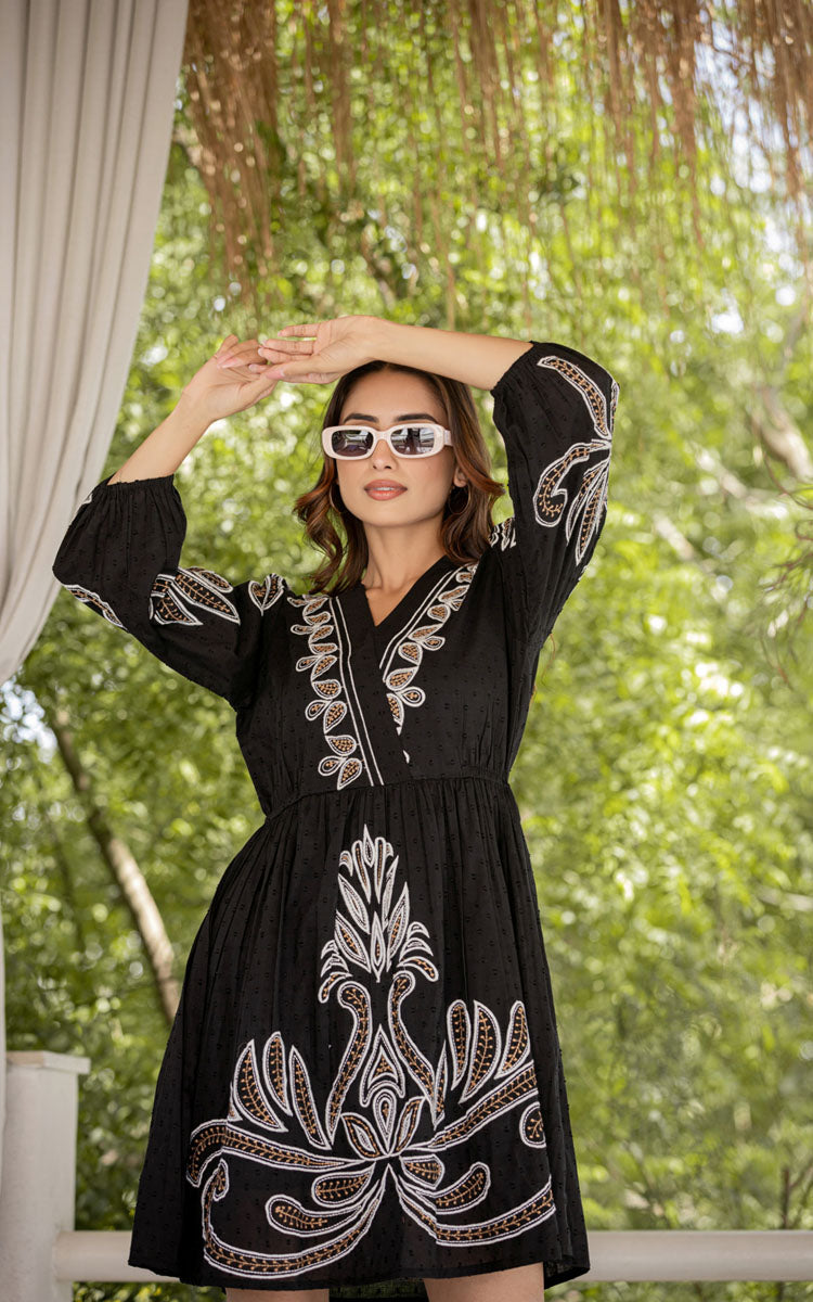 Woman wearing a black dress with white embroidery outdoors