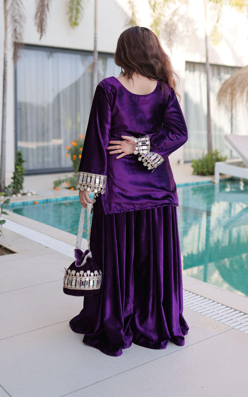 Woman in a purple traditional outfit standing by a poolside.