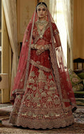 Traditional red bridal outfit with intricate patterns and jewelry in a decorated room.