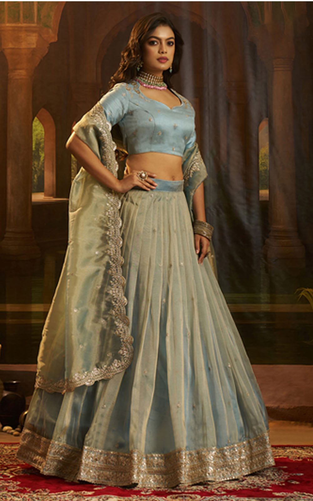 Woman in a traditional light blue outfit with gold details in an ornate setting