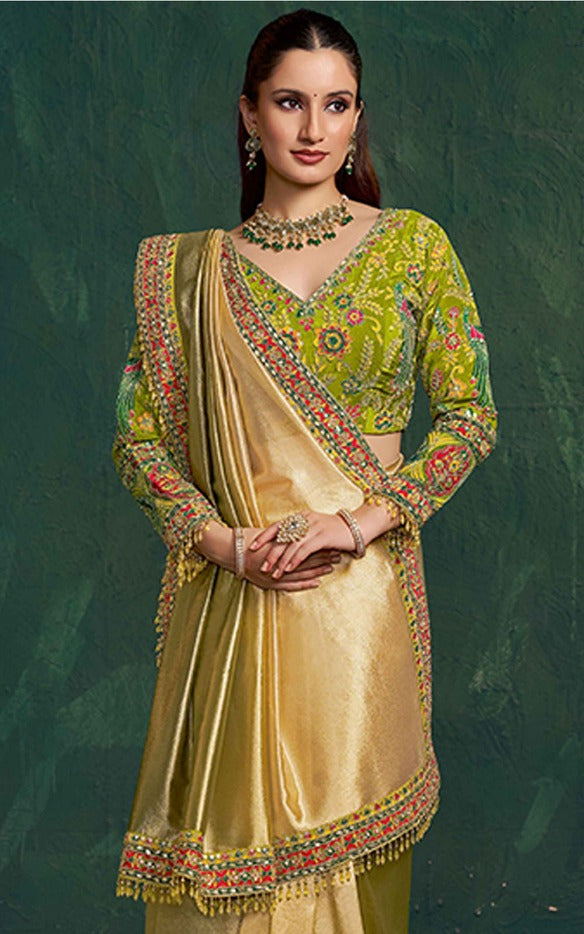 Woman wearing a traditional embroidered outfit with a green and gold color scheme on a dark green background.