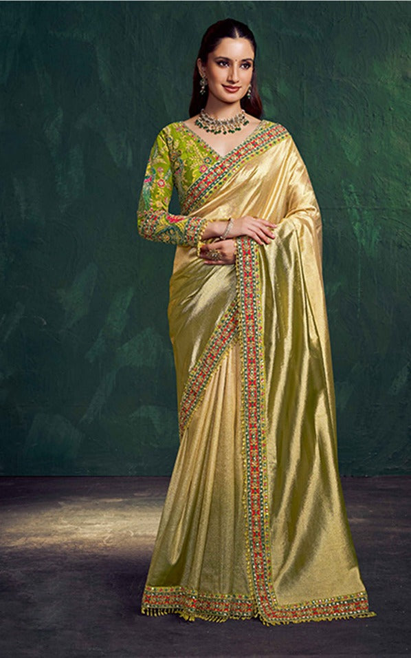 Woman wearing a traditional green and gold saree with a dark background
