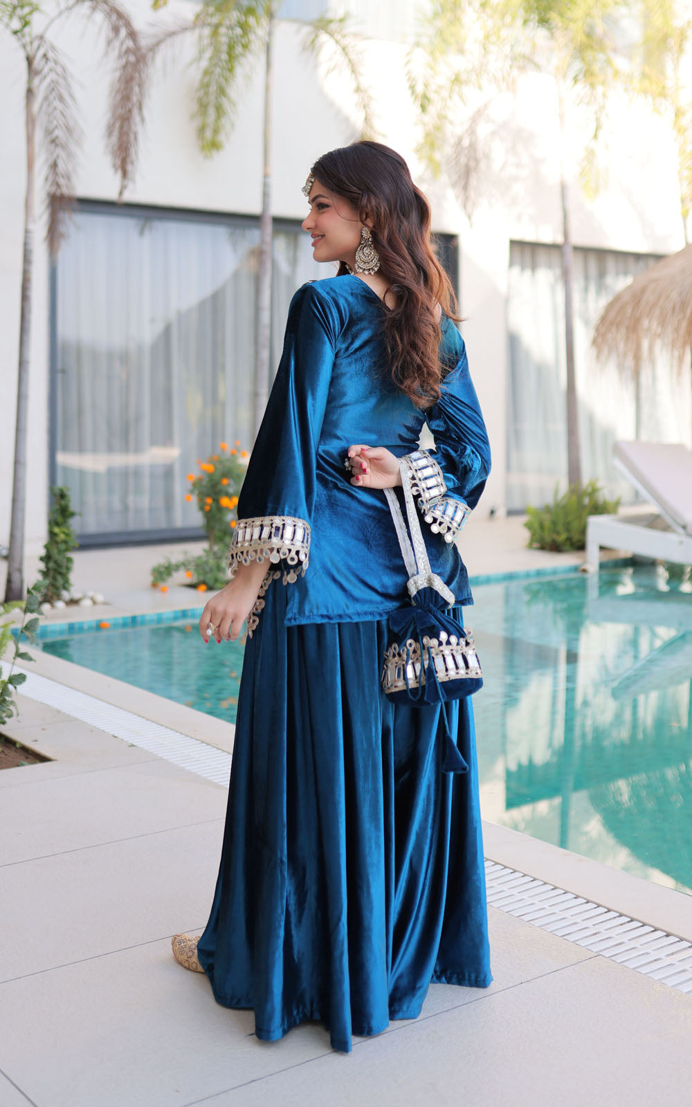 Woman in a blue traditional outfit standing by a poolside.