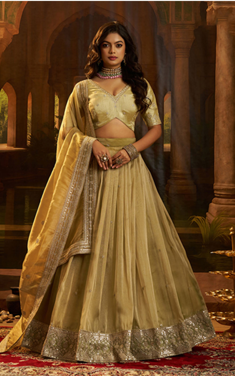 Woman in a traditional green and gold outfit with a decorative background