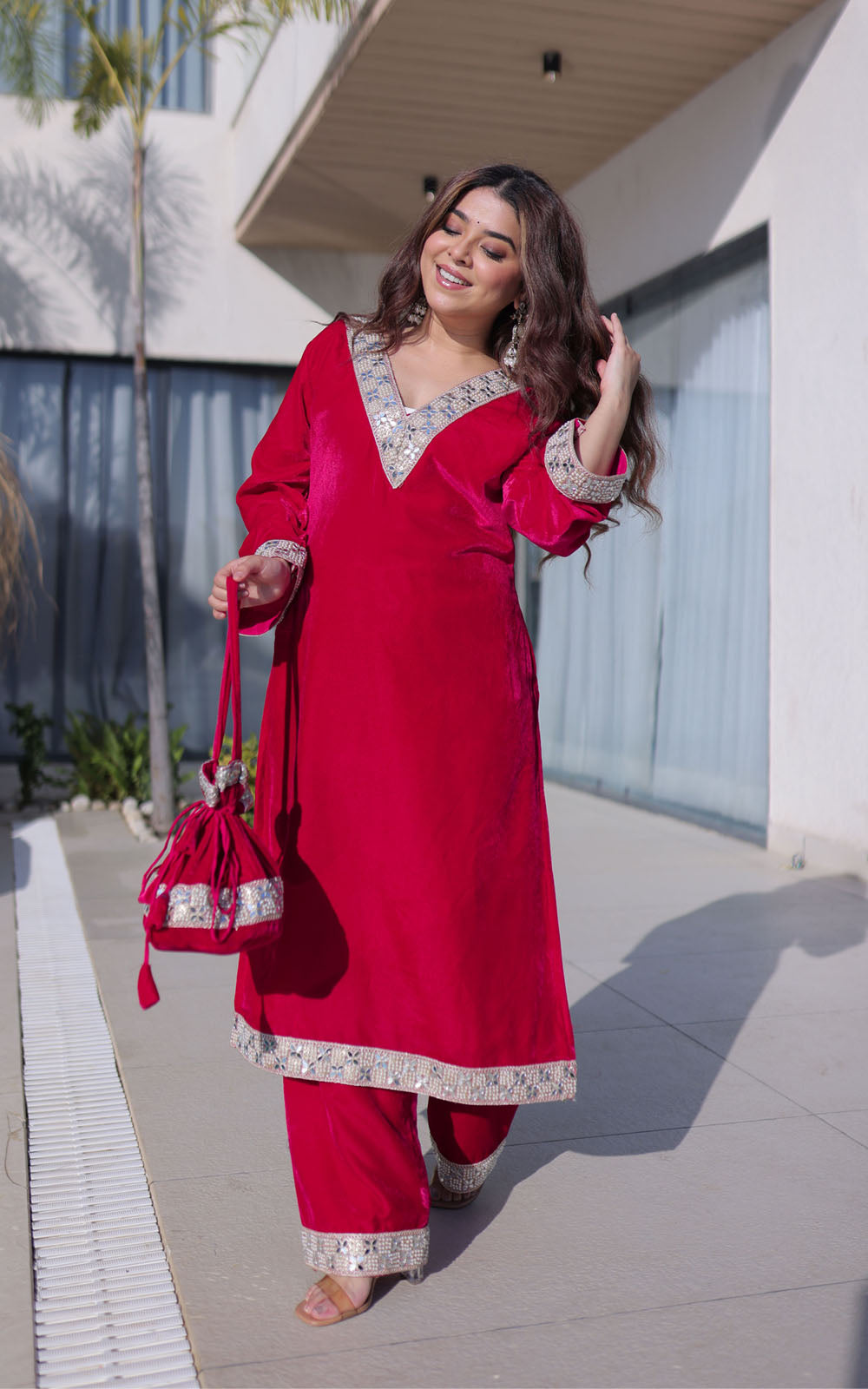 Woman in a red traditional outfit with silver details outdoors.