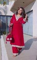 Woman in a red traditional outfit with silver details outdoors.