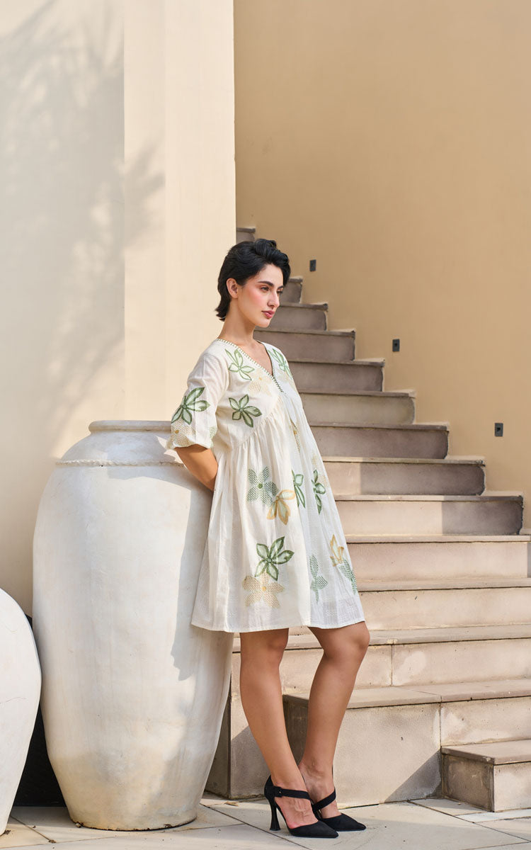 Woman in a floral dress standing on a staircase with a large decorative pot nearby.
