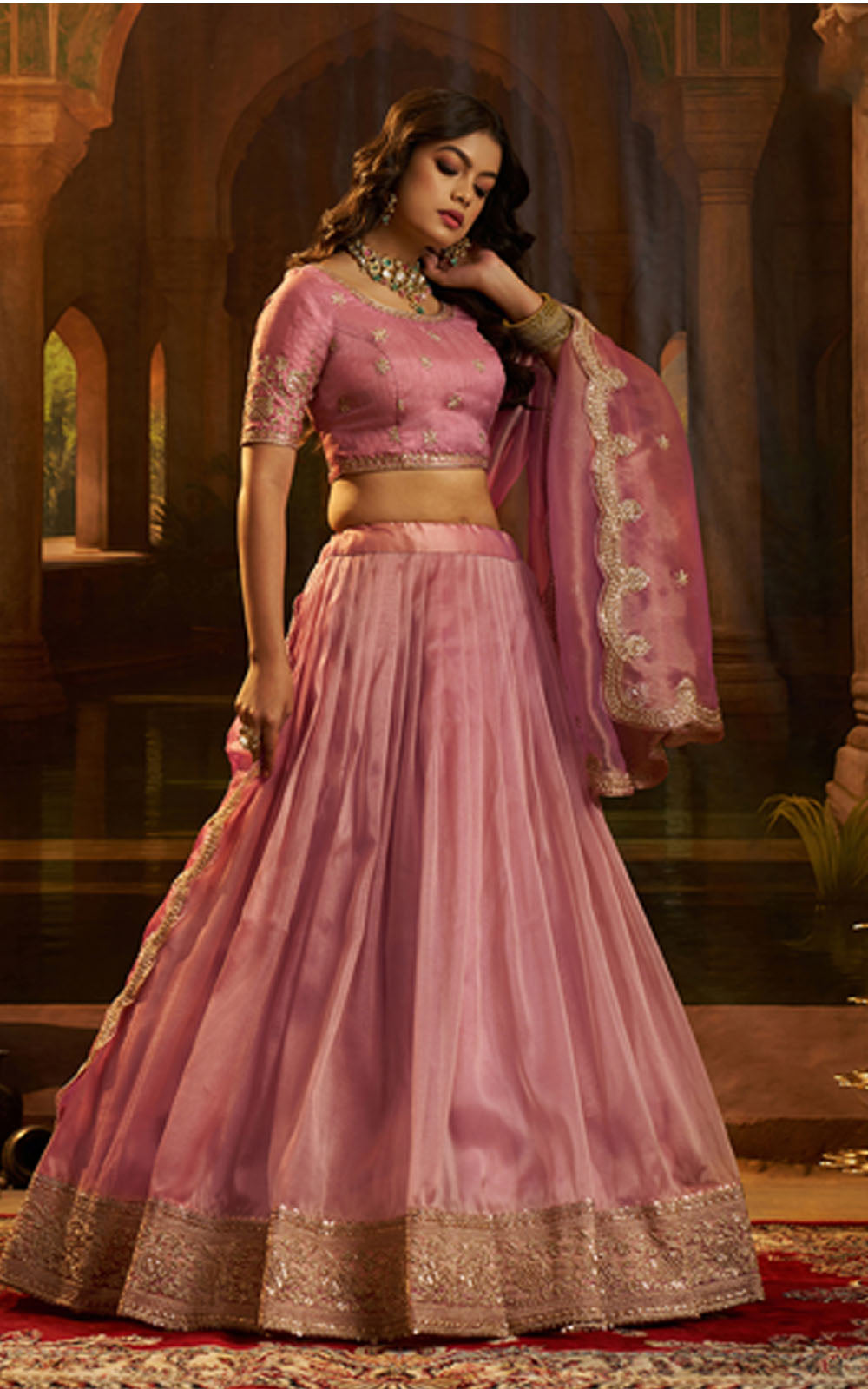 Woman in a pink traditional outfit with gold details in an ornate setting