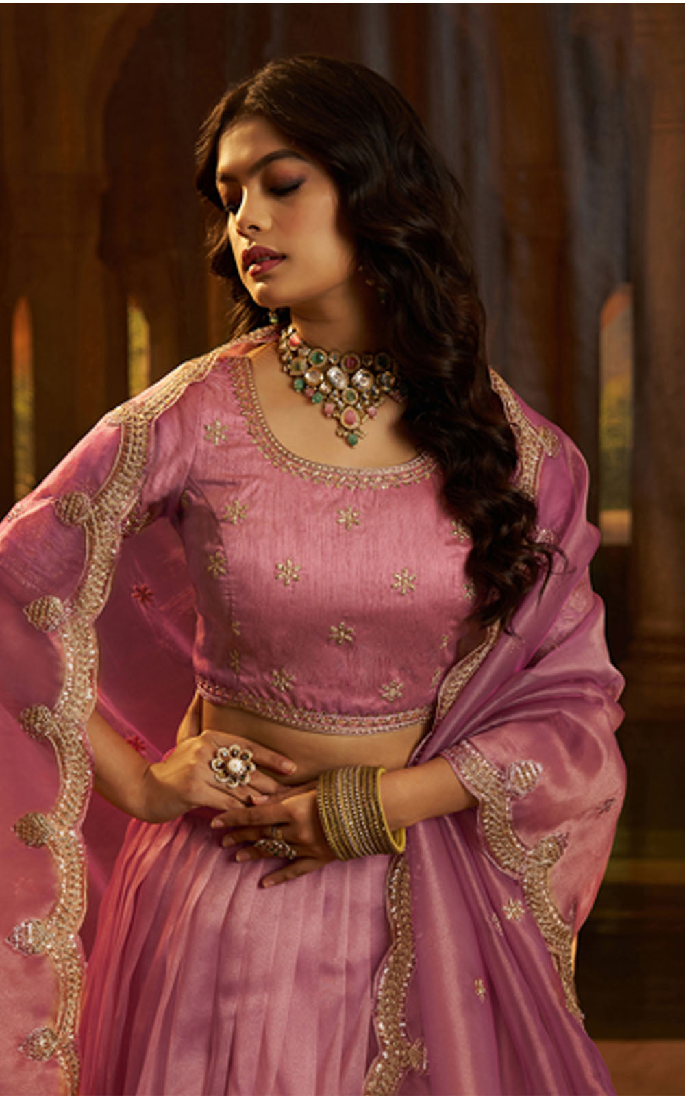 Woman in a pink traditional outfit with jewelry in an indoor setting