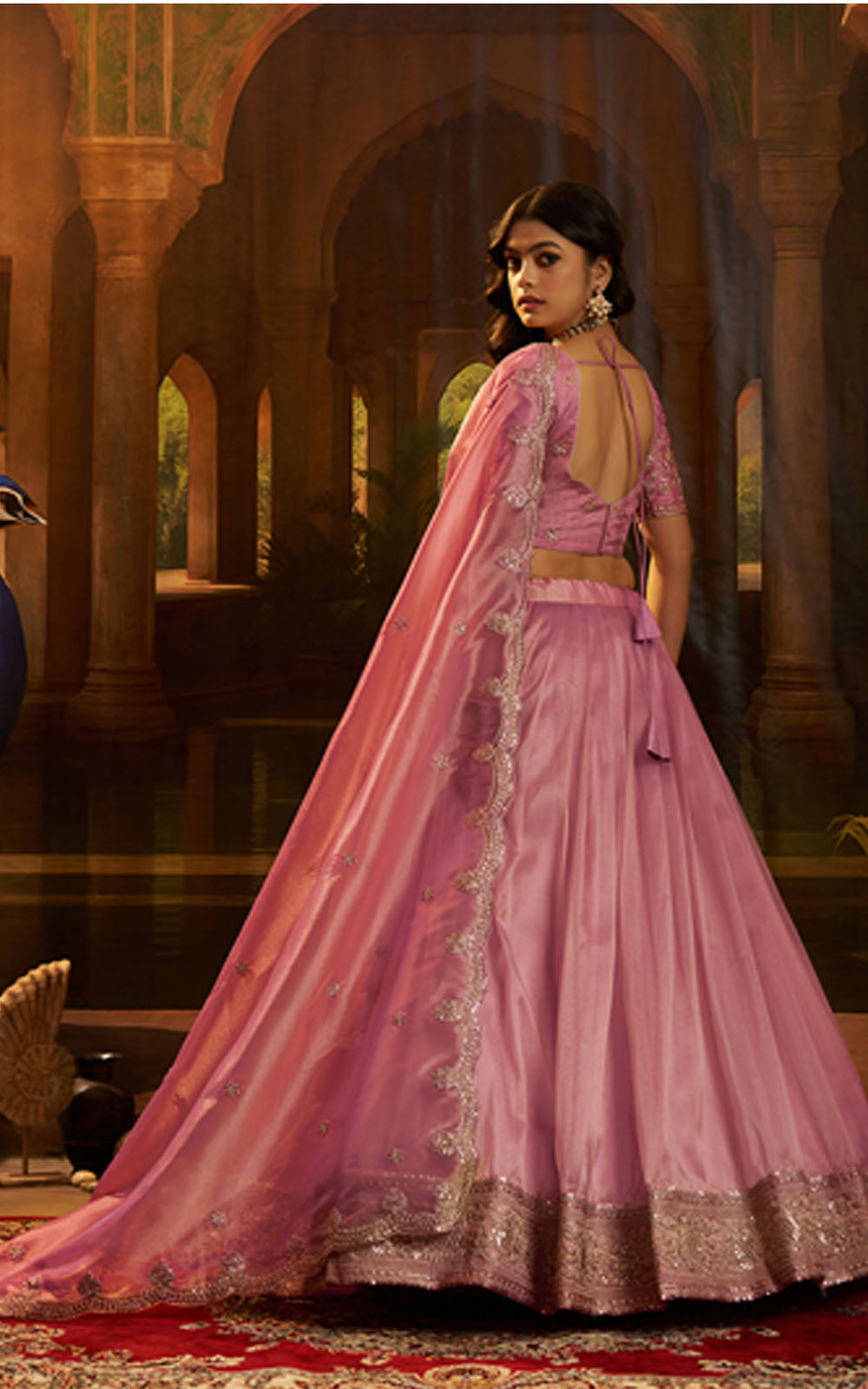Woman in a pink traditional outfit with gold details in an ornate interior setting