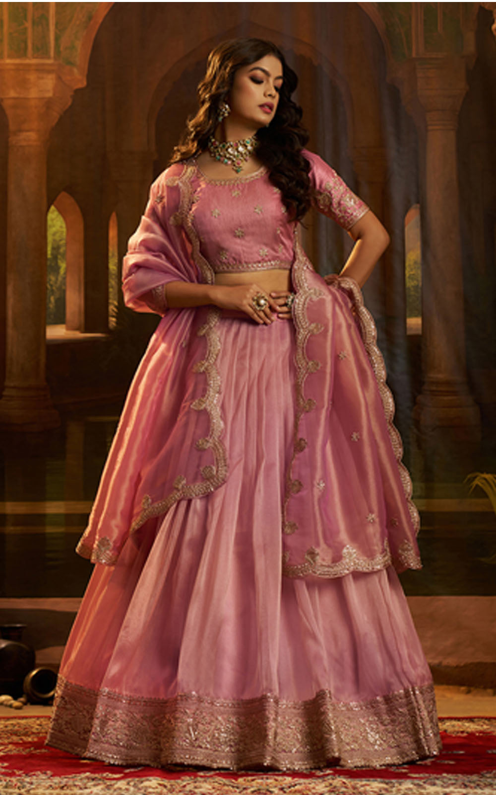 Woman in a pink traditional outfit with intricate designs in a decorative setting