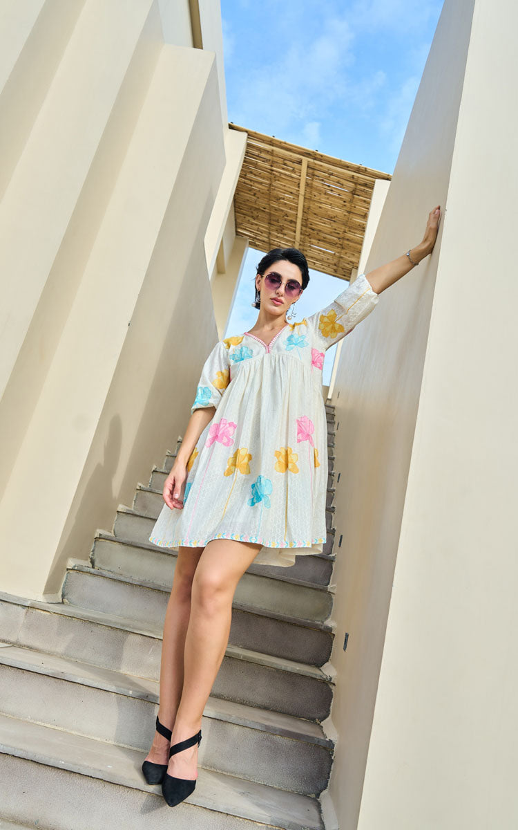 Woman in a colorful dress standing on stone steps with a clear sky background