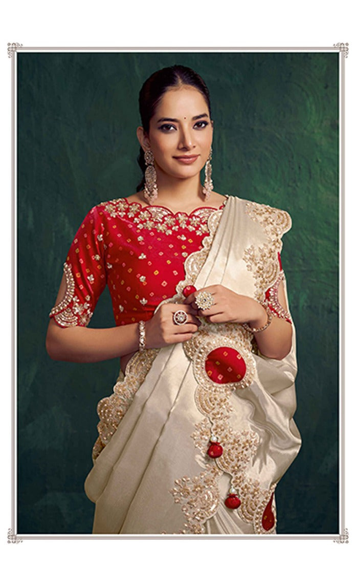 Woman wearing a red and white saree with gold embellishments against a dark green background