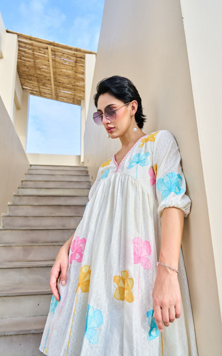 Woman in a colorful dress standing outdoors with steps and columns in the background