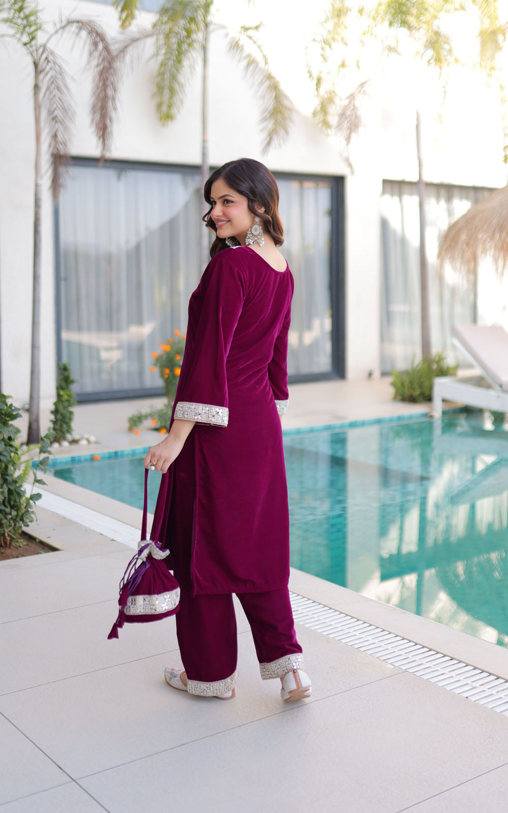 Woman in a maroon traditional outfit standing by a poolside.