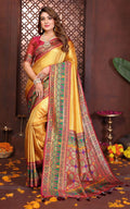 Woman wearing a traditional yellow saree with a colorful border against a decorative background.