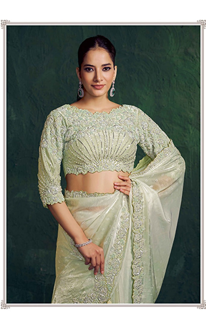 Woman wearing a light green saree with a dark background