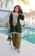 Woman in green traditional outfit by a poolside