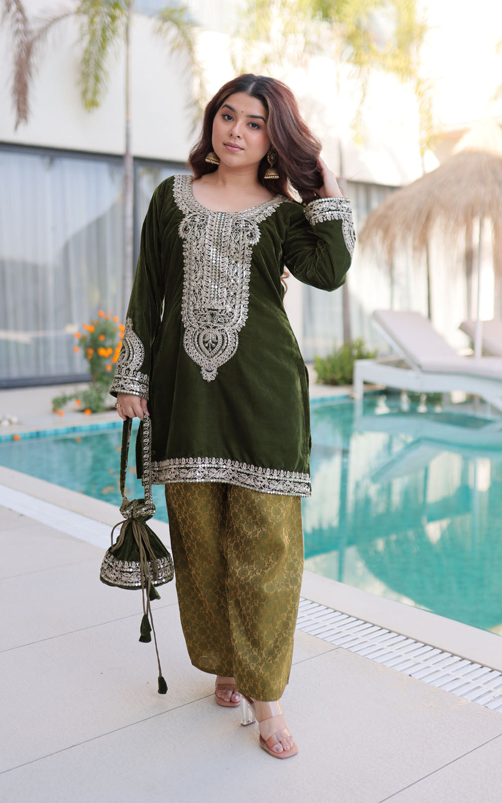 Woman in green traditional outfit by a poolside