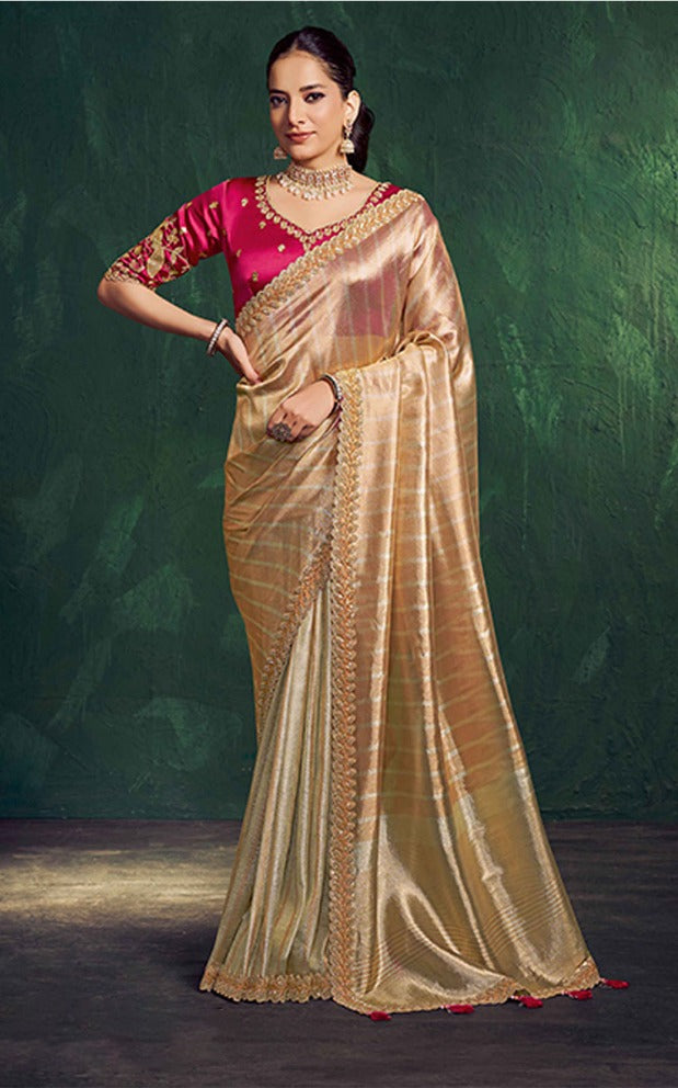 Woman wearing a gold saree with a red blouse against a green background