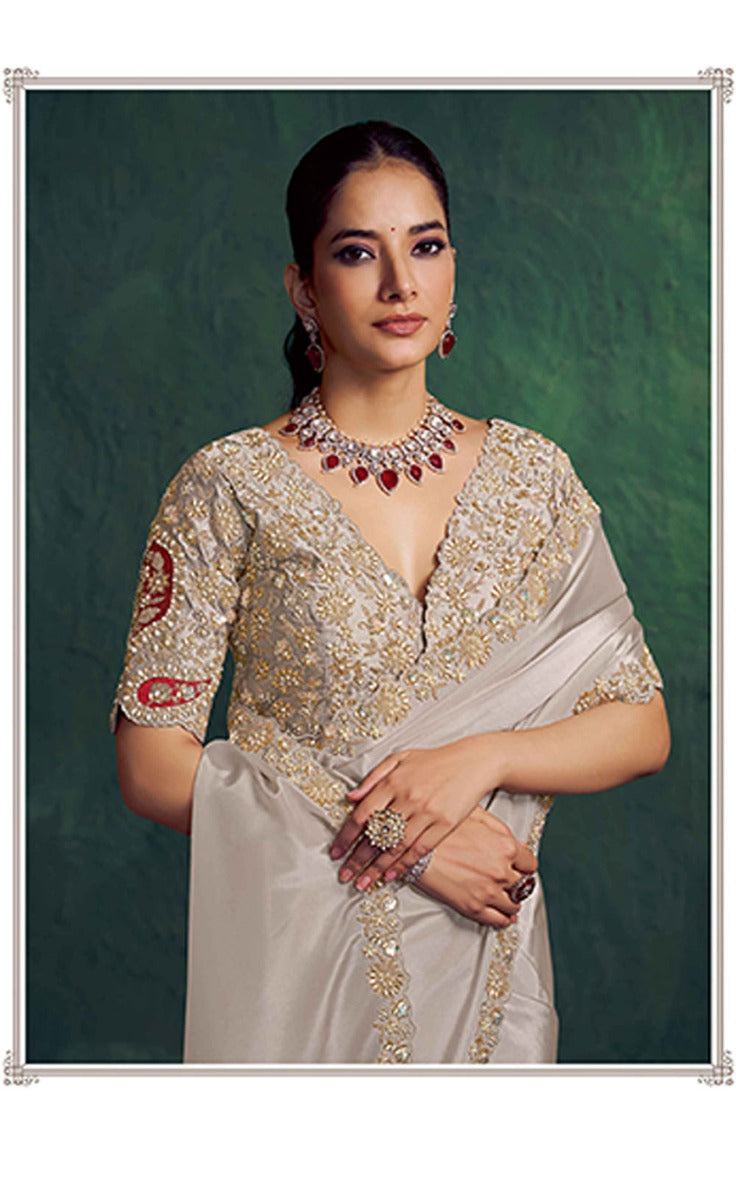 Woman in traditional embroidered blouse and saree against a green background