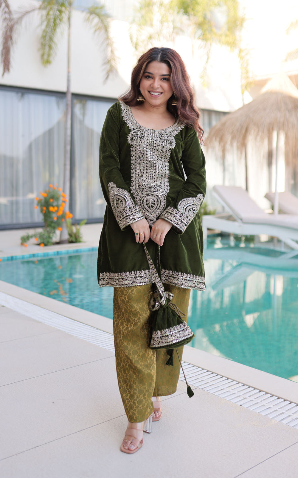 Woman in a green and white outfit standing by a poolside.