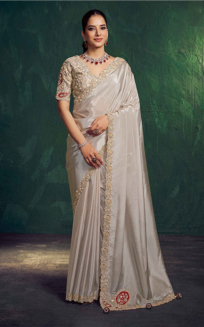 Woman wearing a traditional saree with intricate designs against a dark green background