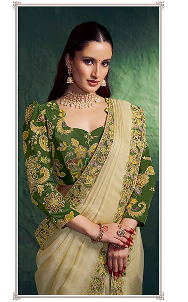 Woman wearing a green and beige saree with intricate patterns against a green background