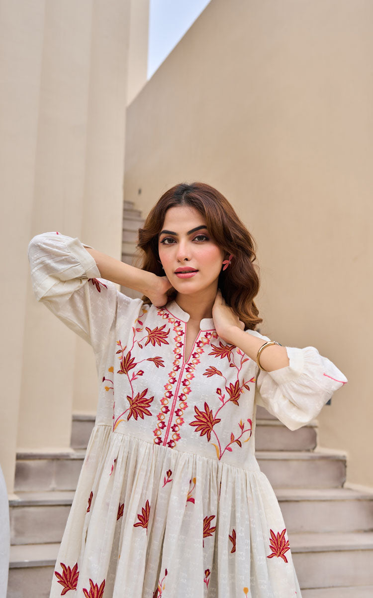 Woman wearing a white dress with red floral embroidery on steps