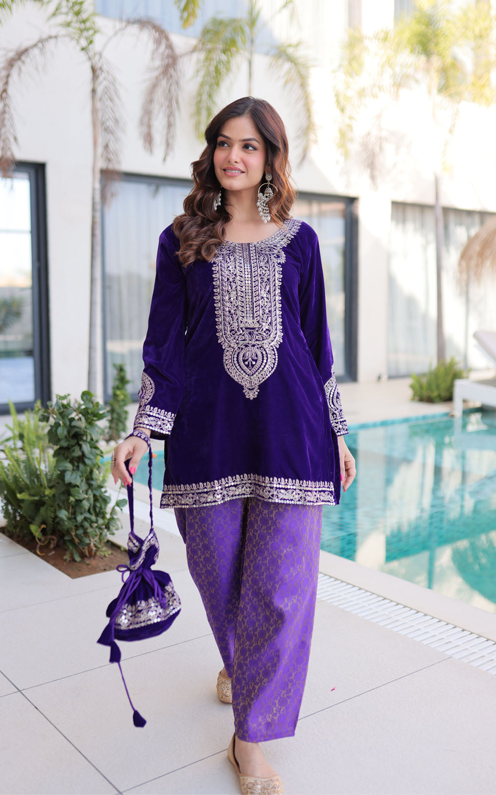 Woman in a purple traditional outfit standing by a pool