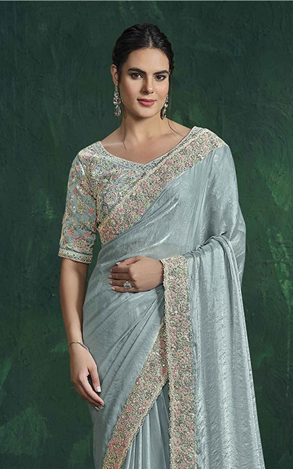 Woman wearing a light blue saree with a green background