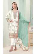 Woman wearing a traditional outfit with white and green dupatta in a well-lit room.