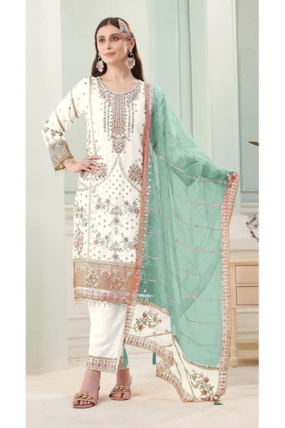 Woman wearing a traditional outfit with white and green dupatta in a well-lit room.