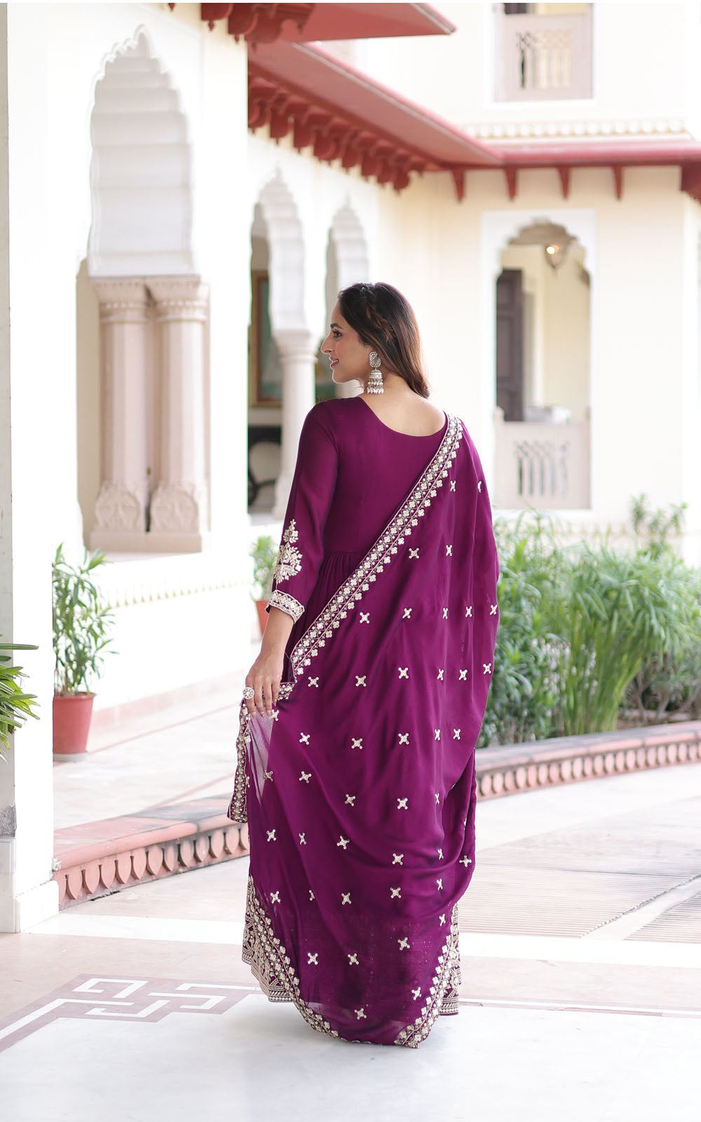 Woman in a purple saree with white patterns standing in an outdoor setting.