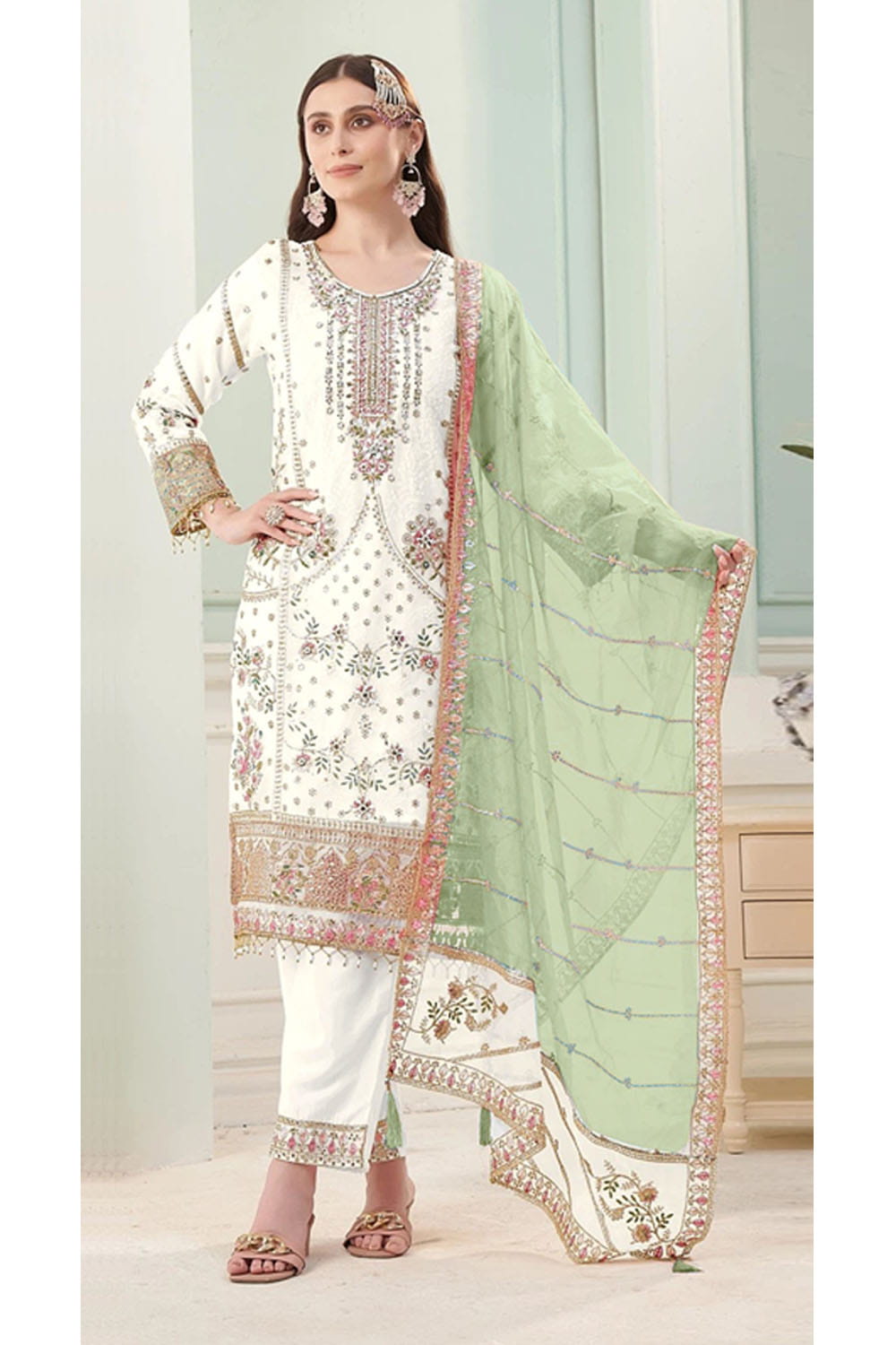 Woman wearing a traditional outfit with white and green dupatta in a well-lit room.