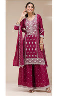 Woman wearing a maroon embroidered traditional outfit with a beige background