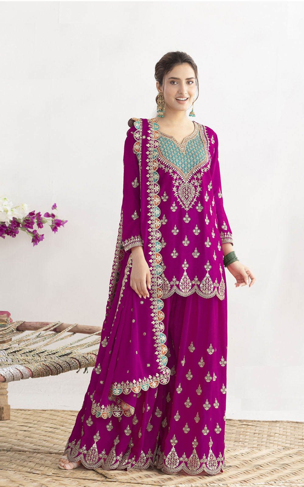 Woman wearing a purple embroidered traditional outfit with a white background