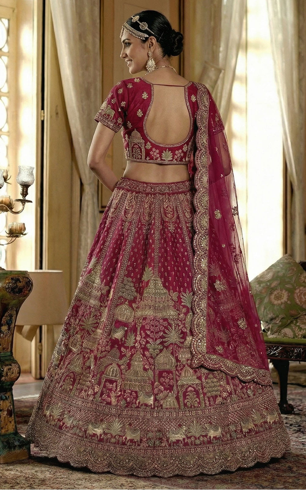 Woman wearing a traditional pink and gold embroidered lehenga in an elegant room.