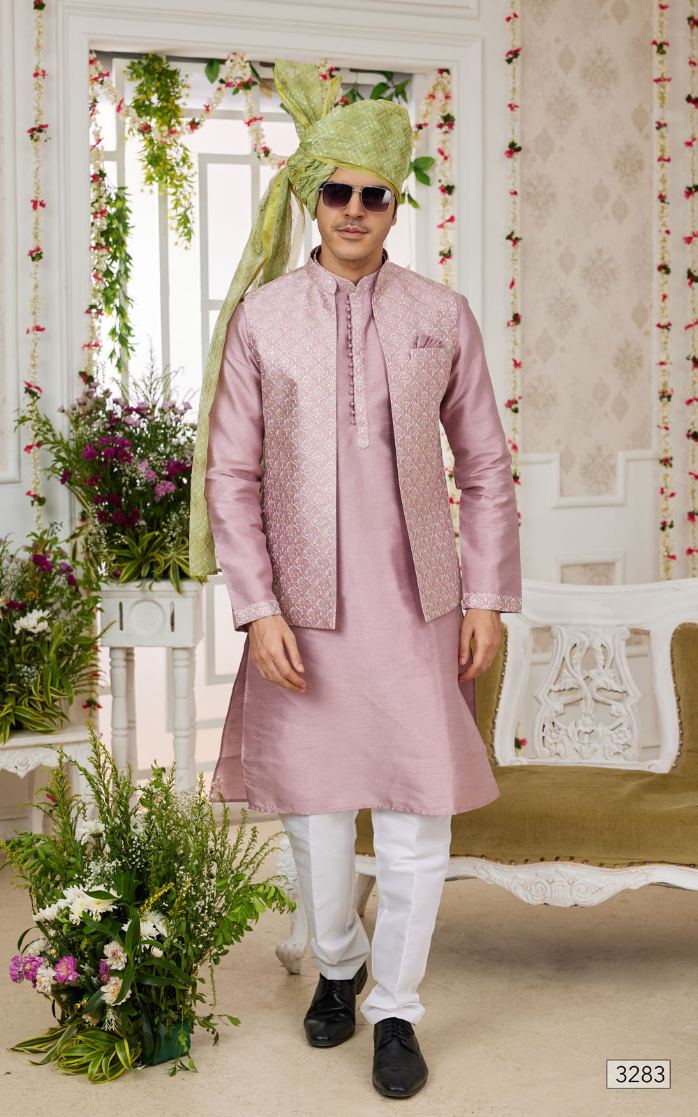 Man wearing a pink sherwani with white pants in a decorated room.