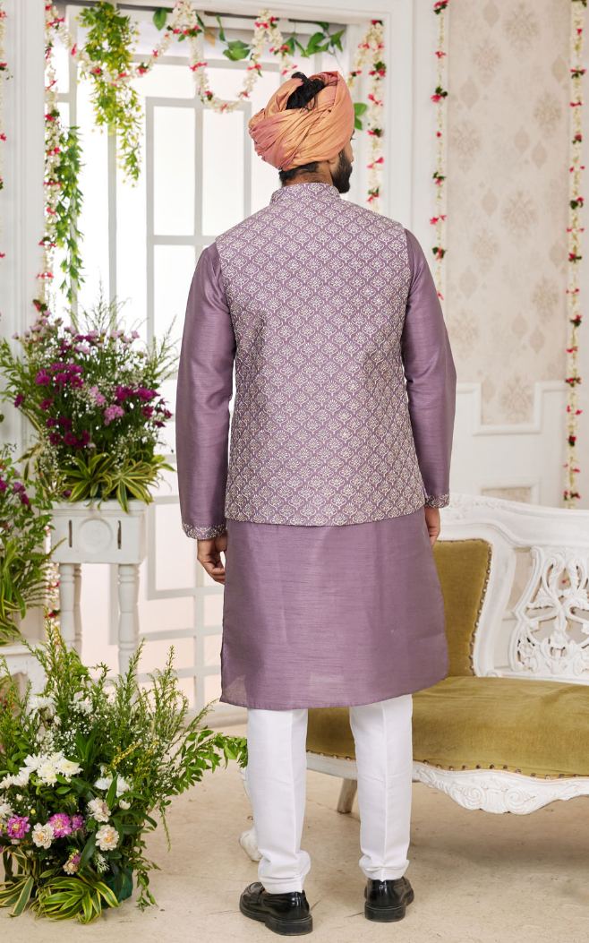 Man wearing a traditional purple kurta with a matching vest in a decorated indoor setting.