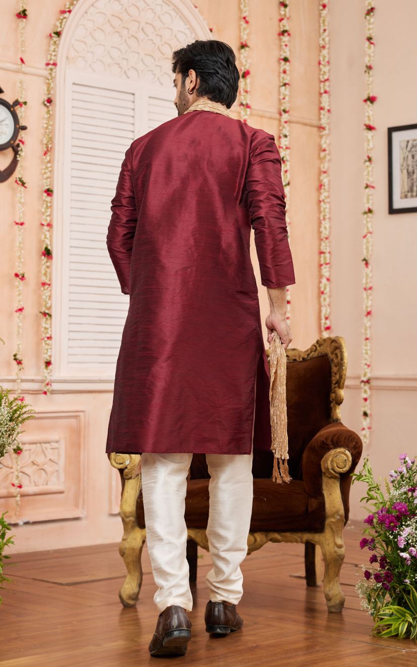 Man wearing a maroon kurta with white pants in an indoor setting.