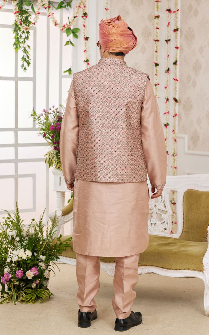Person wearing a traditional beige kurta with a matching jacket in a decorated indoor setting.