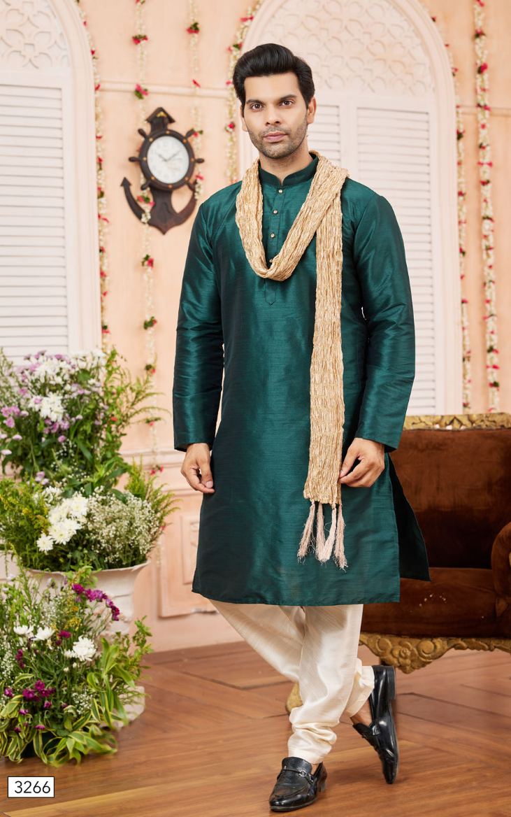 Man wearing a green kurta with white pants and a beige scarf in a decorated room.