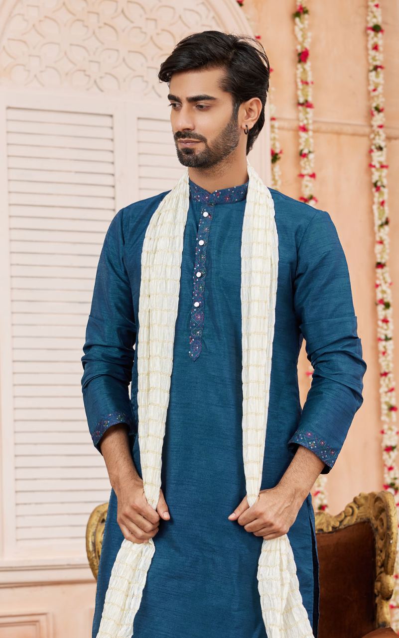 Man wearing a blue kurta with a white scarf in an indoor setting